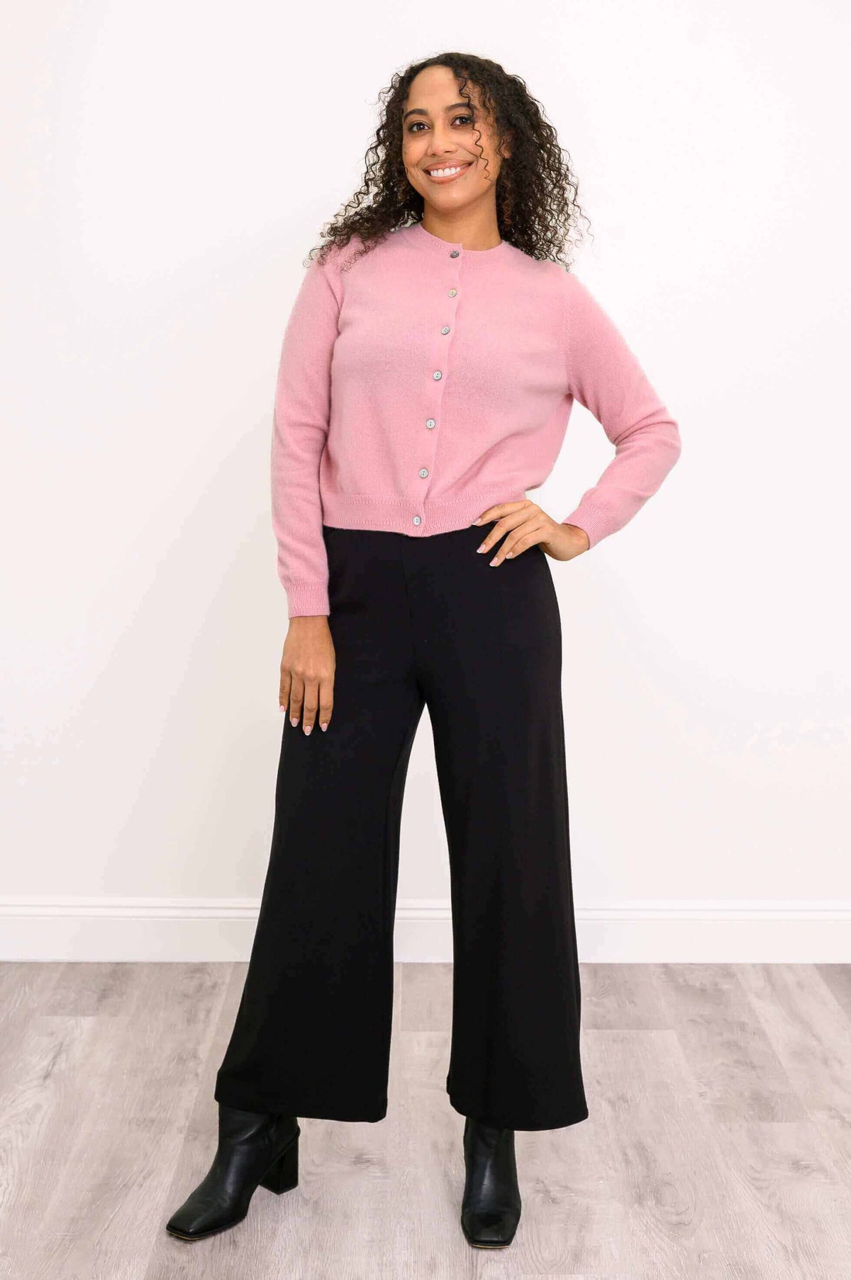 Front angled view of pink cashmere cardigan styled with black pants