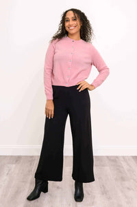 Front angled view of pink cashmere cardigan styled with black pants