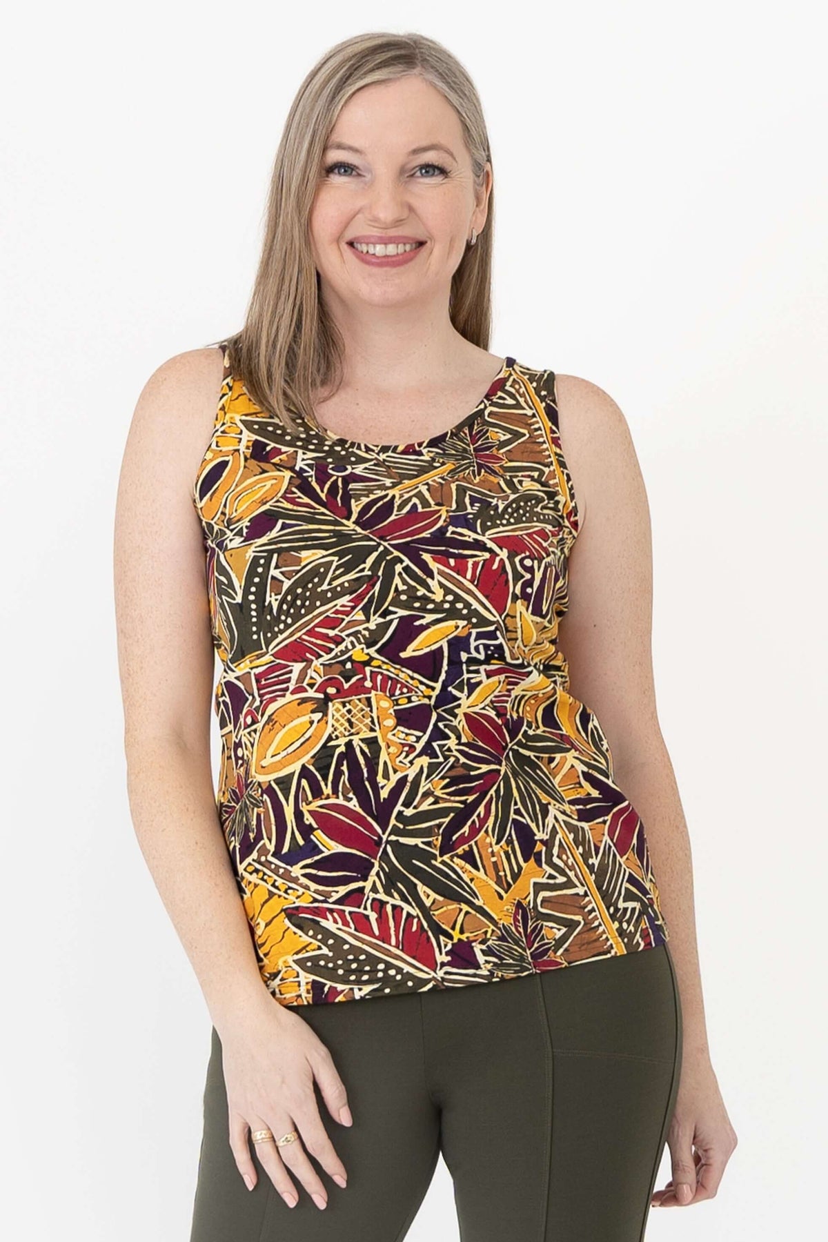 Woman wearing a sleeveless tank top with vibrant marigold batik pattern, close up front view