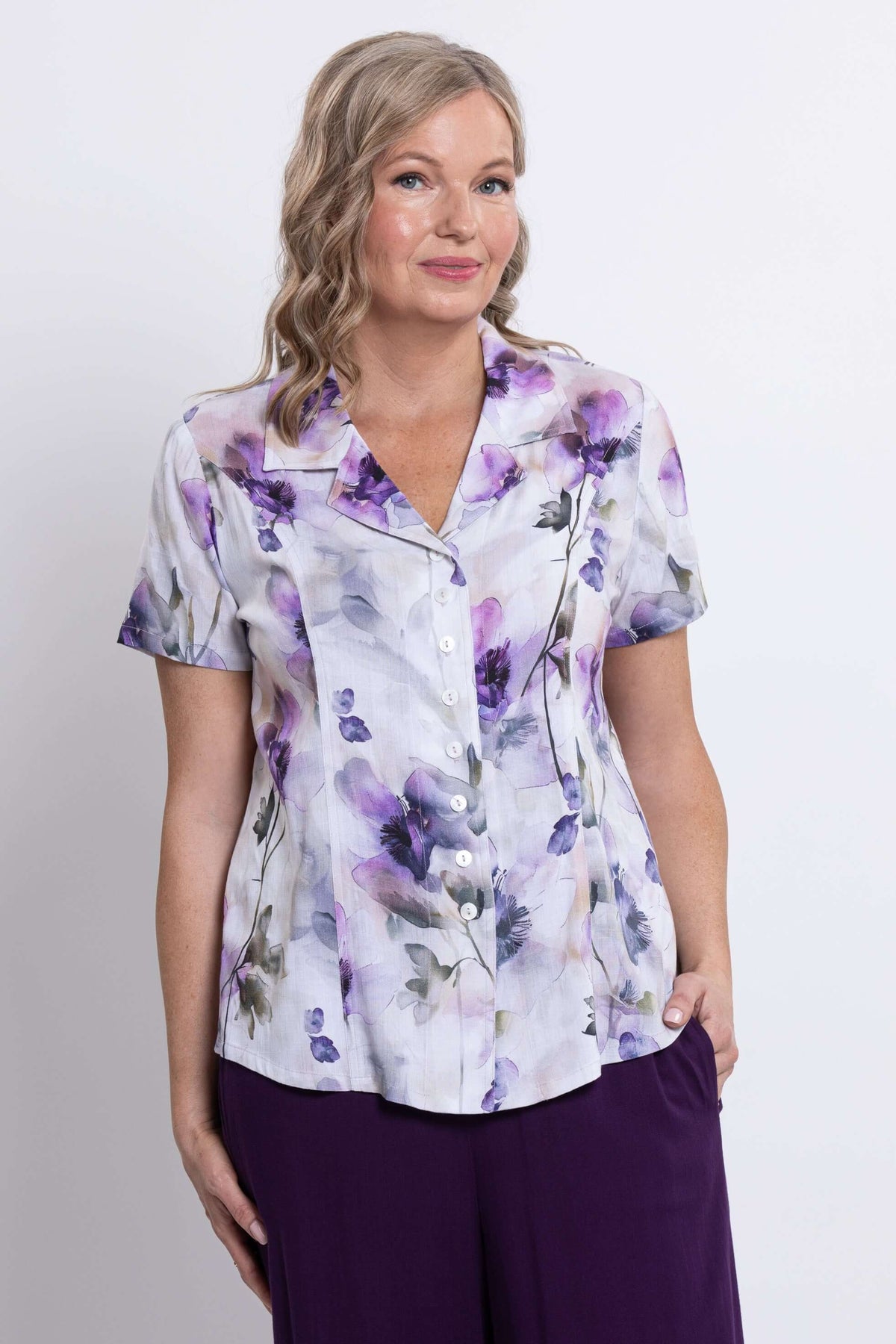 Woman wearing a short-sleeve button-up shirt with purple floral print, front view, close-up