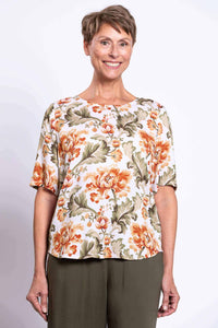 Woman wearing a floral print elbow-sleeve blouse with green pants, front view close-up