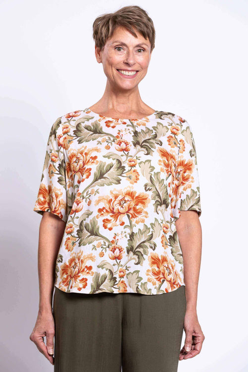 Woman wearing a floral print elbow-sleeve blouse with green pants, front view close-up