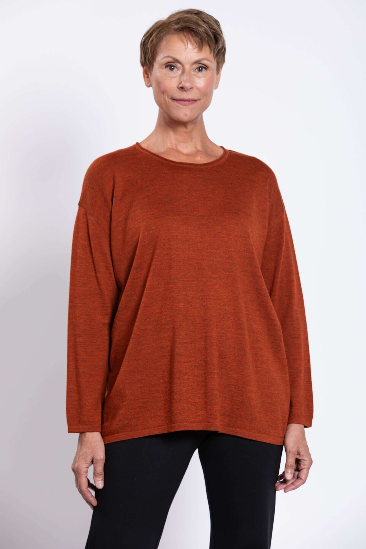 Front close-up of woman wearing a rust red boxy long sleeve Merino wool sweater