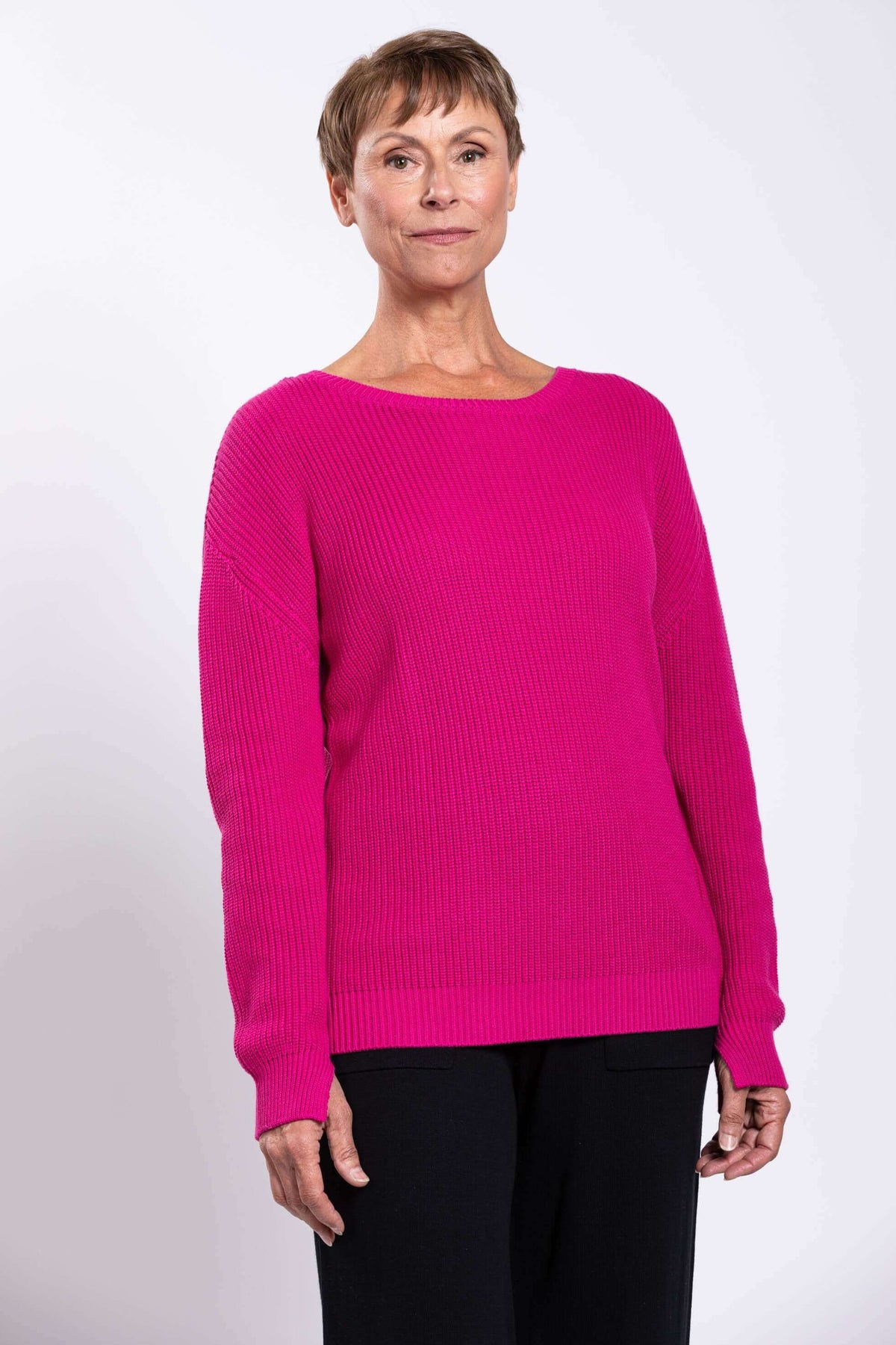 Front close-up view of a woman wearing a bright fuchsia shaker stitch sweater