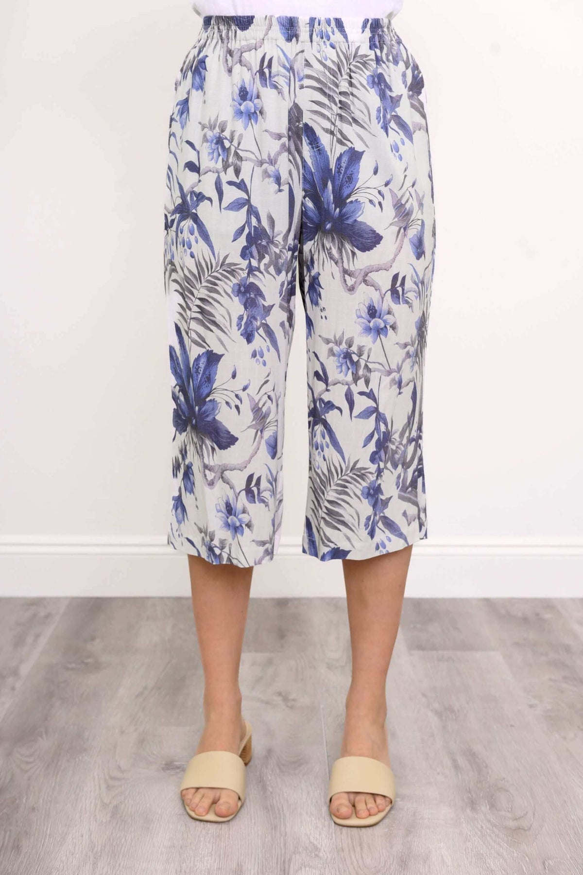 Front close-up of blue floral capri pants with elastic waistband styled with cream sandals