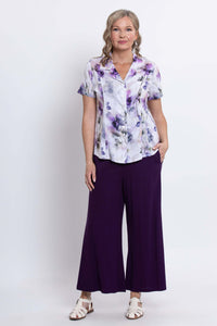 Woman modeling a short-sleeve purple floral blouse with matching purple pants, full body, front view