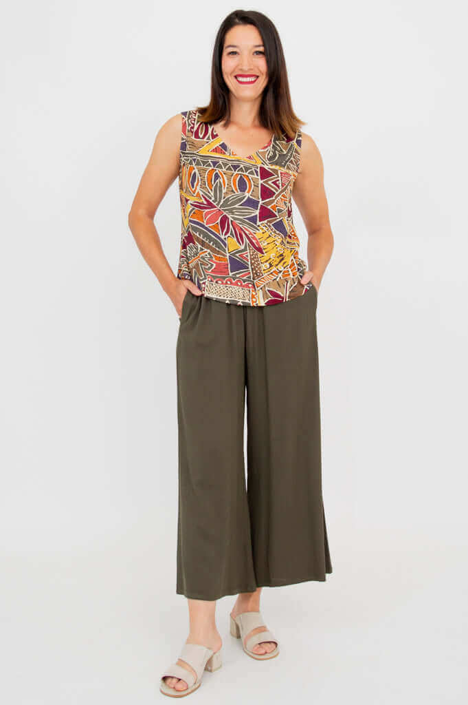 Front full-length view of a woman in a graphic print tank and olive green pants