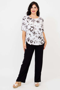 Woman standing in white floral print blouse and black pants, front full body shot