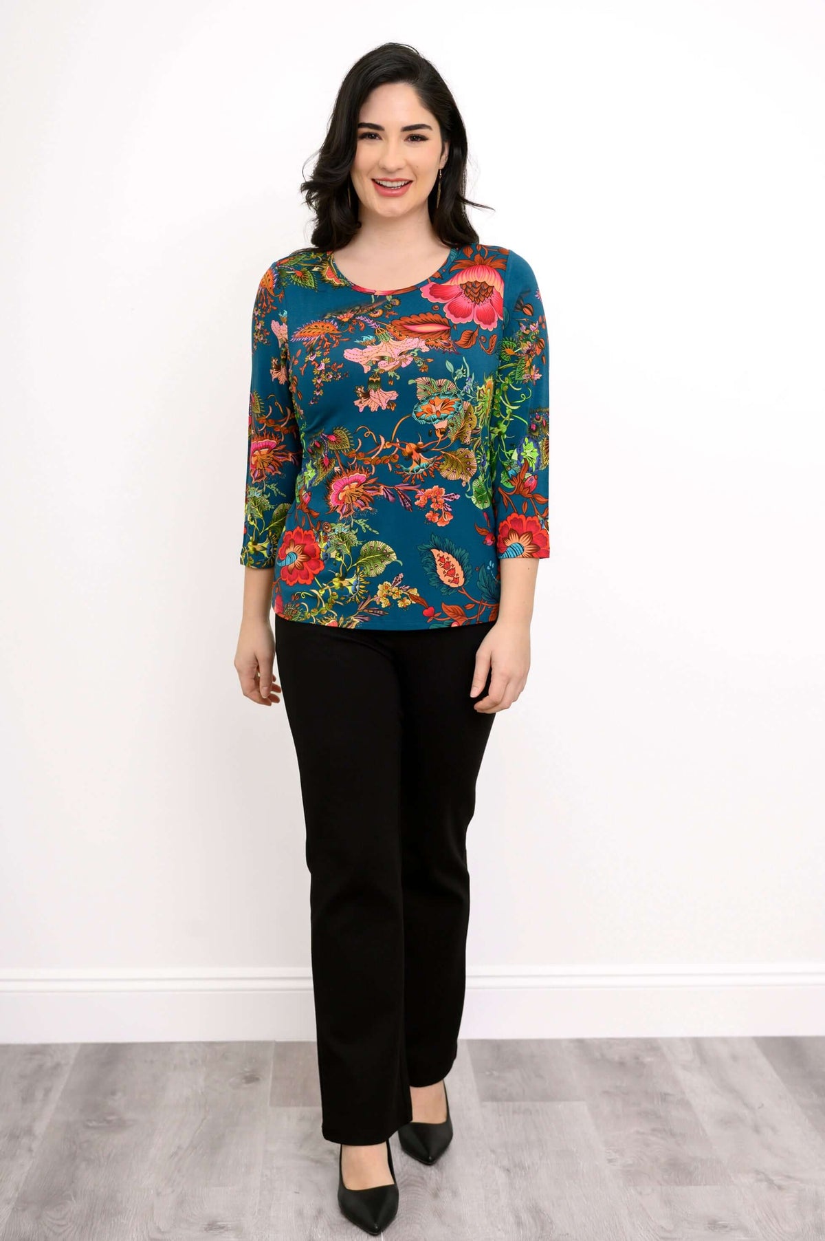 Full front view of woman modeling a teal floral bamboo top with black pants
