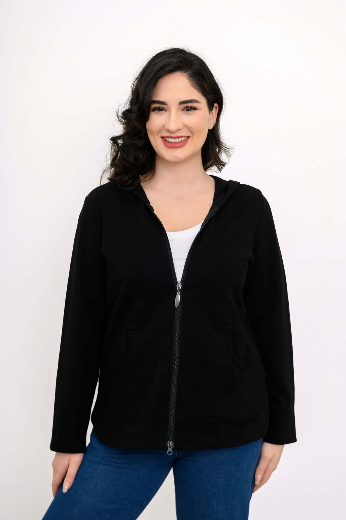 Front view of a woman wearing a black zip-up hoodie with a white top underneath