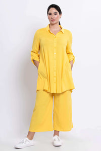 Model in sunflower yellow tunic has hands in side seam pockets, front view