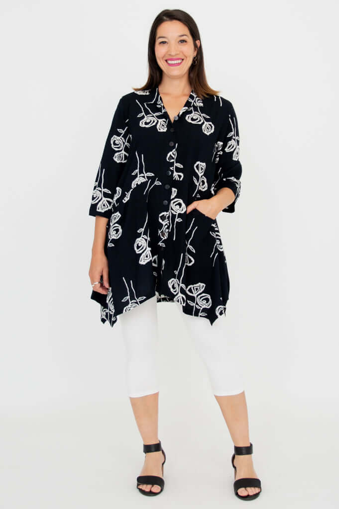 Woman posing in black tunic with white rose sketches and 3/4 sleeves, front view