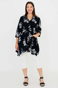 Woman posing in black tunic with white rose sketches and 3/4 sleeves, front view