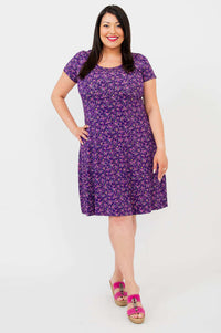 Model in Callie Bamboo Dress, hands on hip, violet floral pattern front view