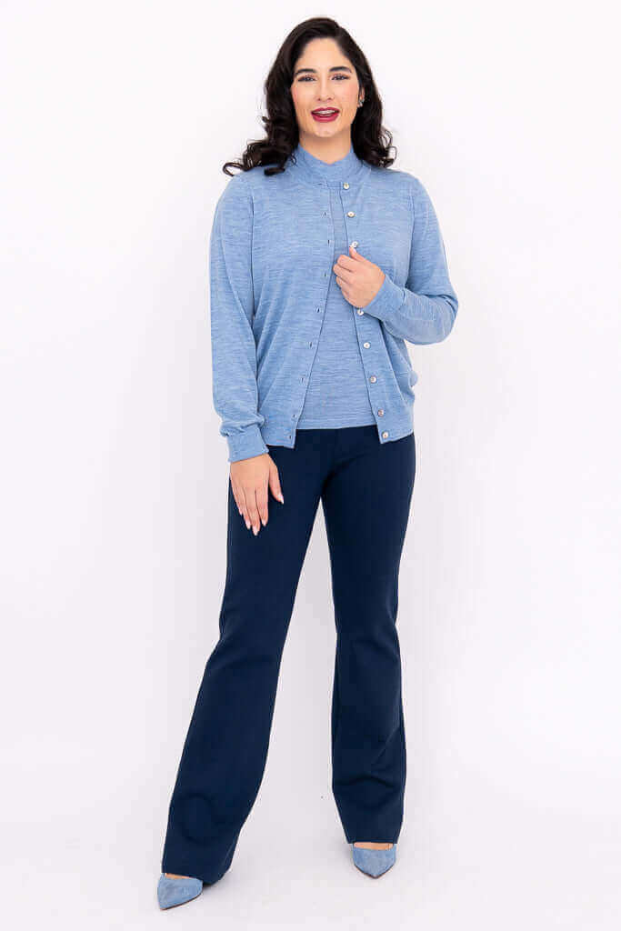 Woman in blue cardigan and navy pants, front view, hand on sweater