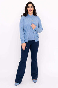 Woman in blue cardigan and navy pants, front view, hand on sweater