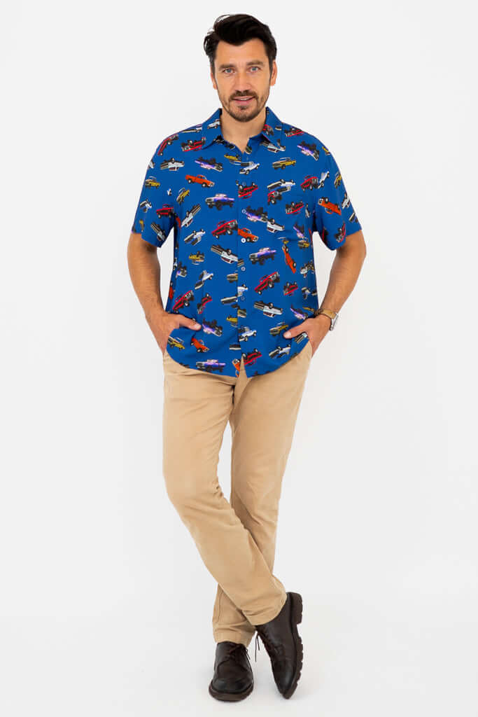 Man standing with arms in pockets wearing blue monster truck print shirt