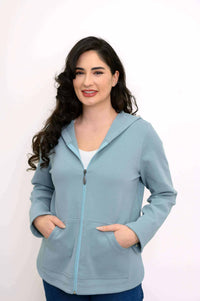 Woman wearing light blue zip-up hoodie jacket facing forward with hands in pockets