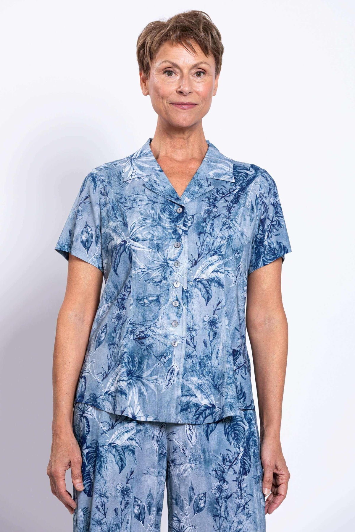 Front pose of woman in blue floral print shirt and matching bottoms, short sleeves and buttons
