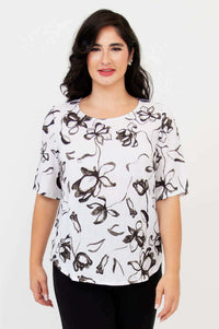 Front view of woman wearing white blouse with black floral print