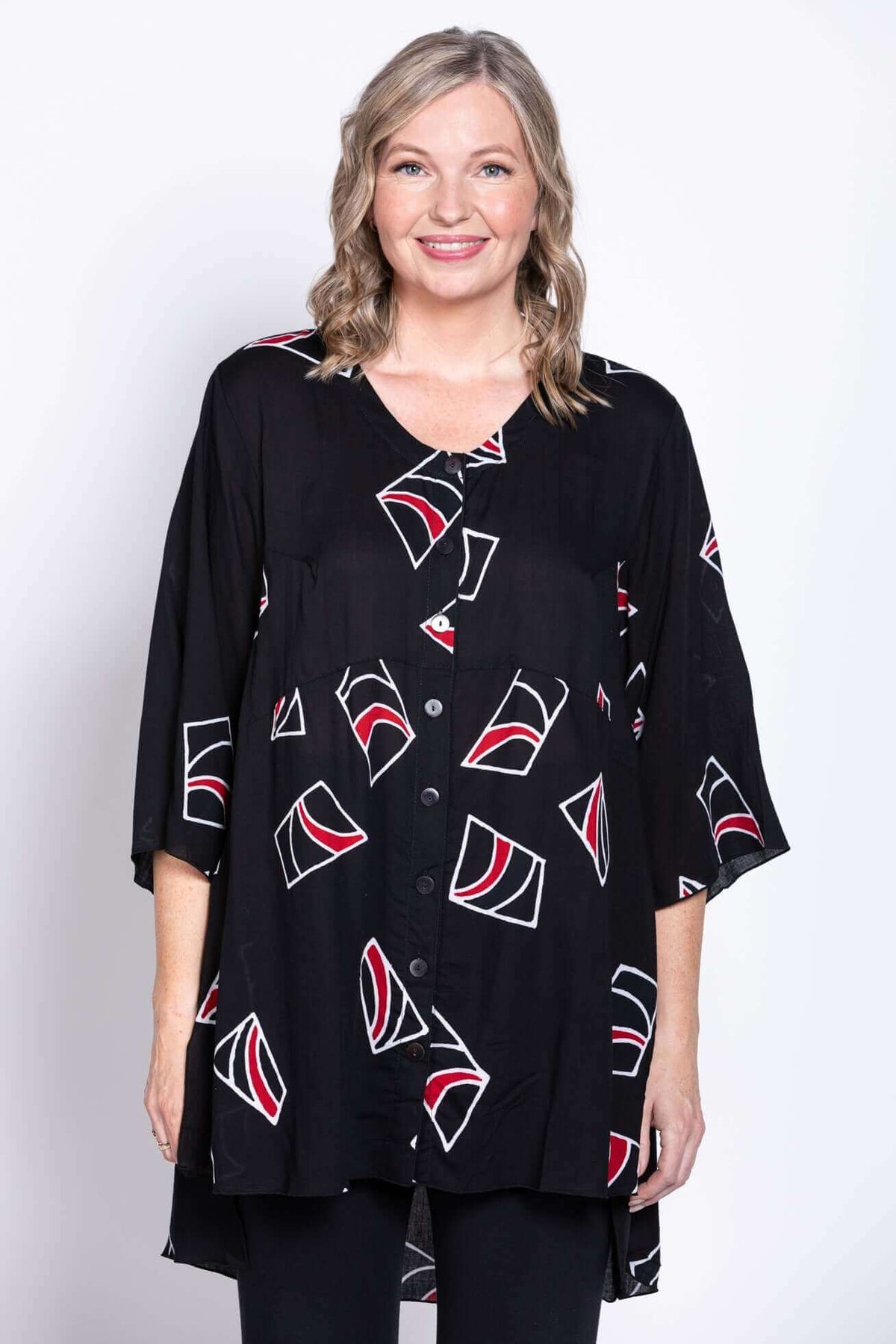 Front view of a woman wearing a black tunic blouse with abstract red and white patterns
