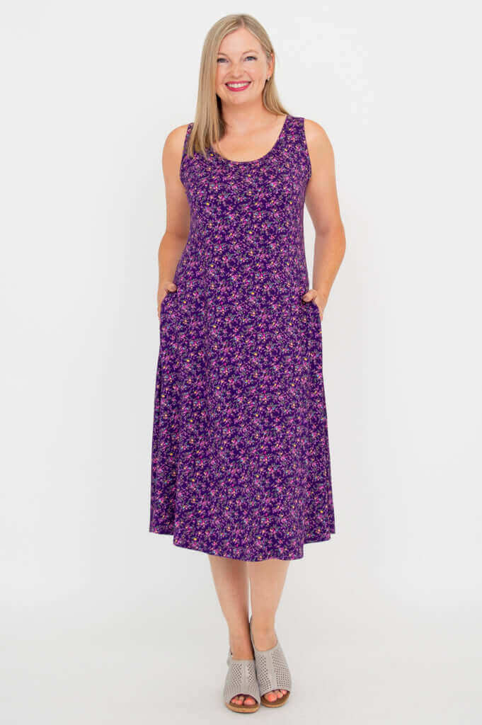 Front view of woman wearing a purple floral Evangelina tank dress with pockets