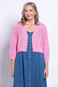 Front view of model wearing pink pointelle knit cropped cardigan over denim dress 
