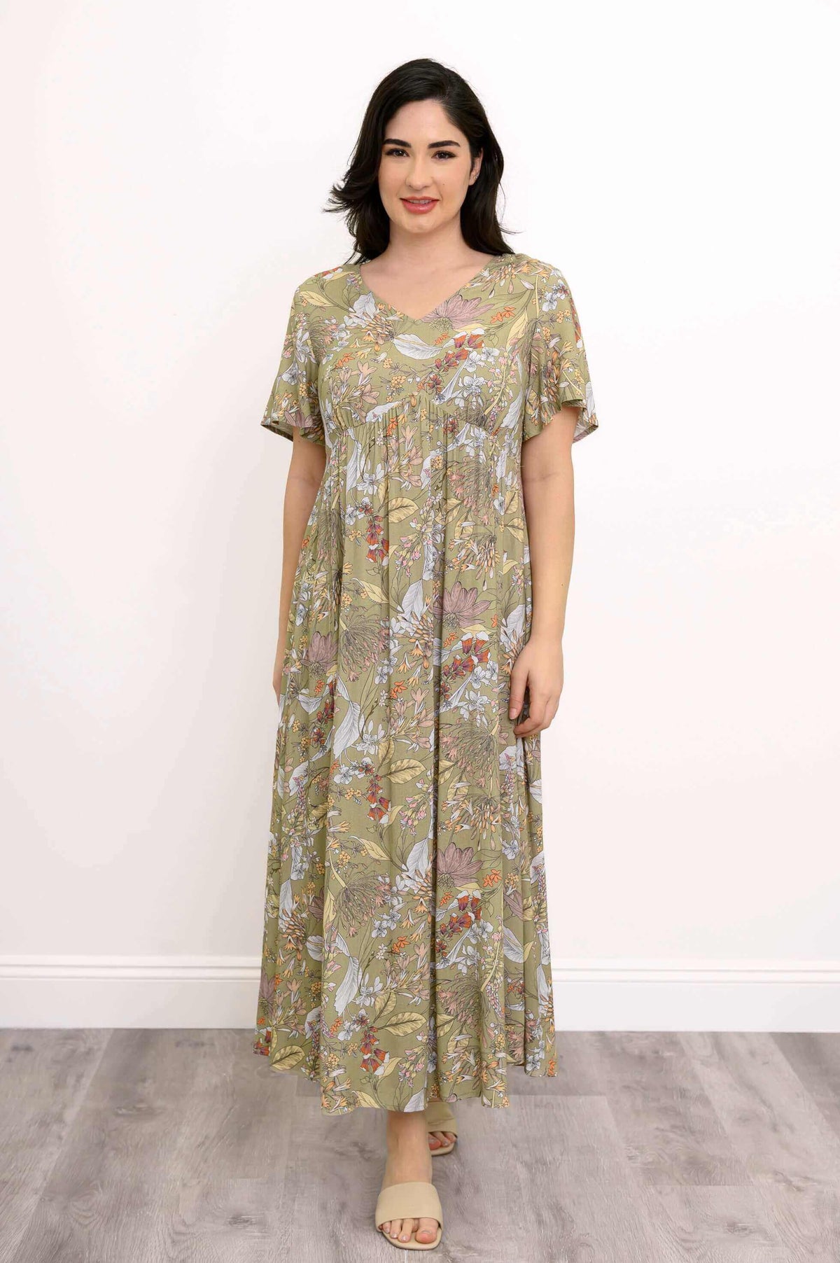 Front view of a woman wearing a green floral maxi dress with flutter sleeves
