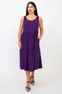 Front view of woman wearing plum sleeveless tiered dress with pockets
