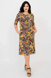 Front view of woman wearing Olivia dress in colorful Tropikal print with hands in pockets