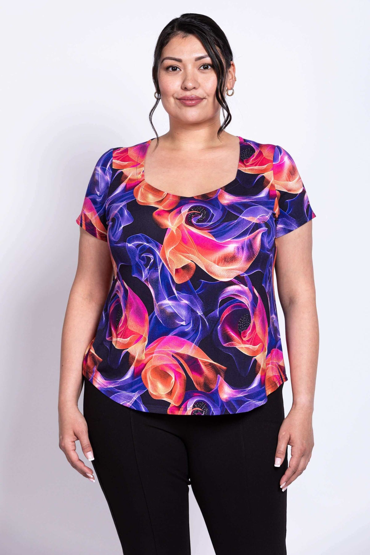 Front view of model wearing short-sleeve top with sweetheart neckline and  bright swirl pattern 