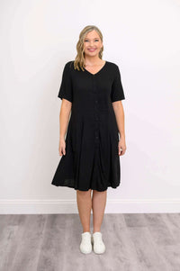 Front view of a woman in a black short-sleeve, button-front dress with pockets
