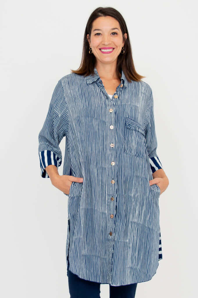 Front view of a woman wearing a blue and white striped oversized shirt with side pockets