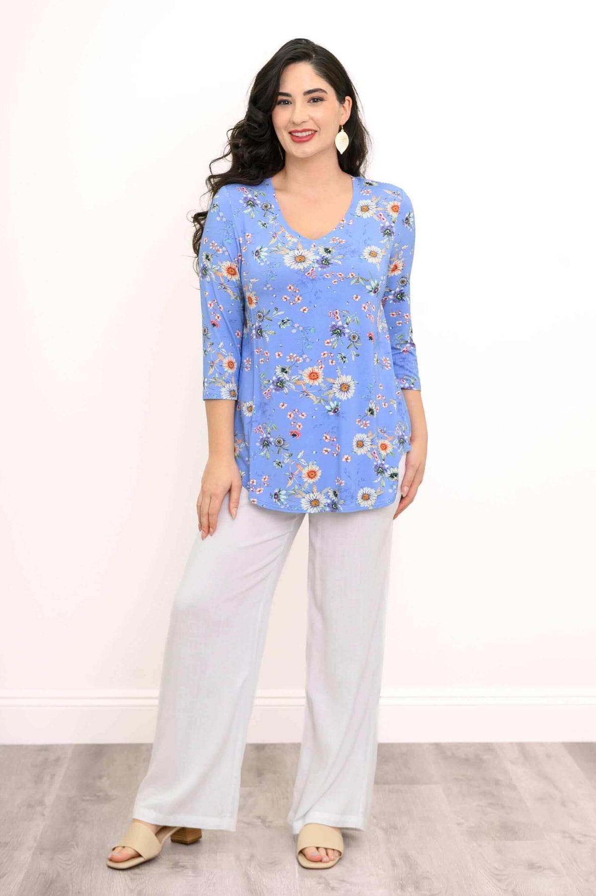 Front view of a woman in a blue V-neck floral top and white pants