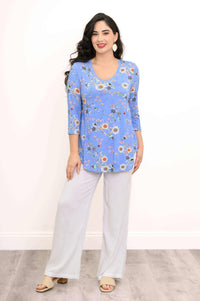 Front view of a woman in a blue V-neck floral top and white pants