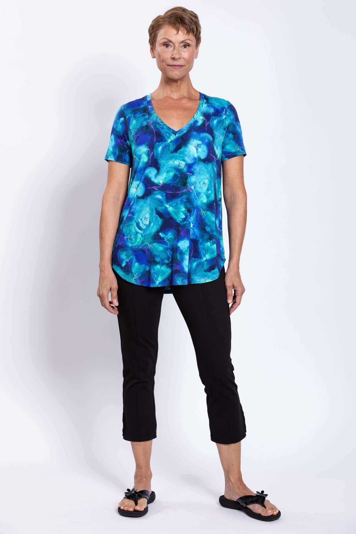 Woman modeling blue floral V-neck top with black cropped pants, front view