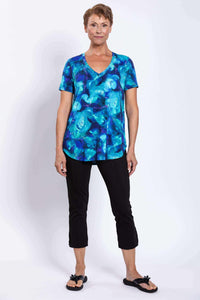 Woman modeling blue floral V-neck top with black cropped pants, front view
