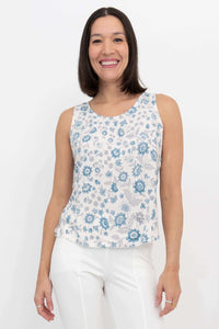 Front view of woman wearing a blue floral scoop neck tank top and white pants