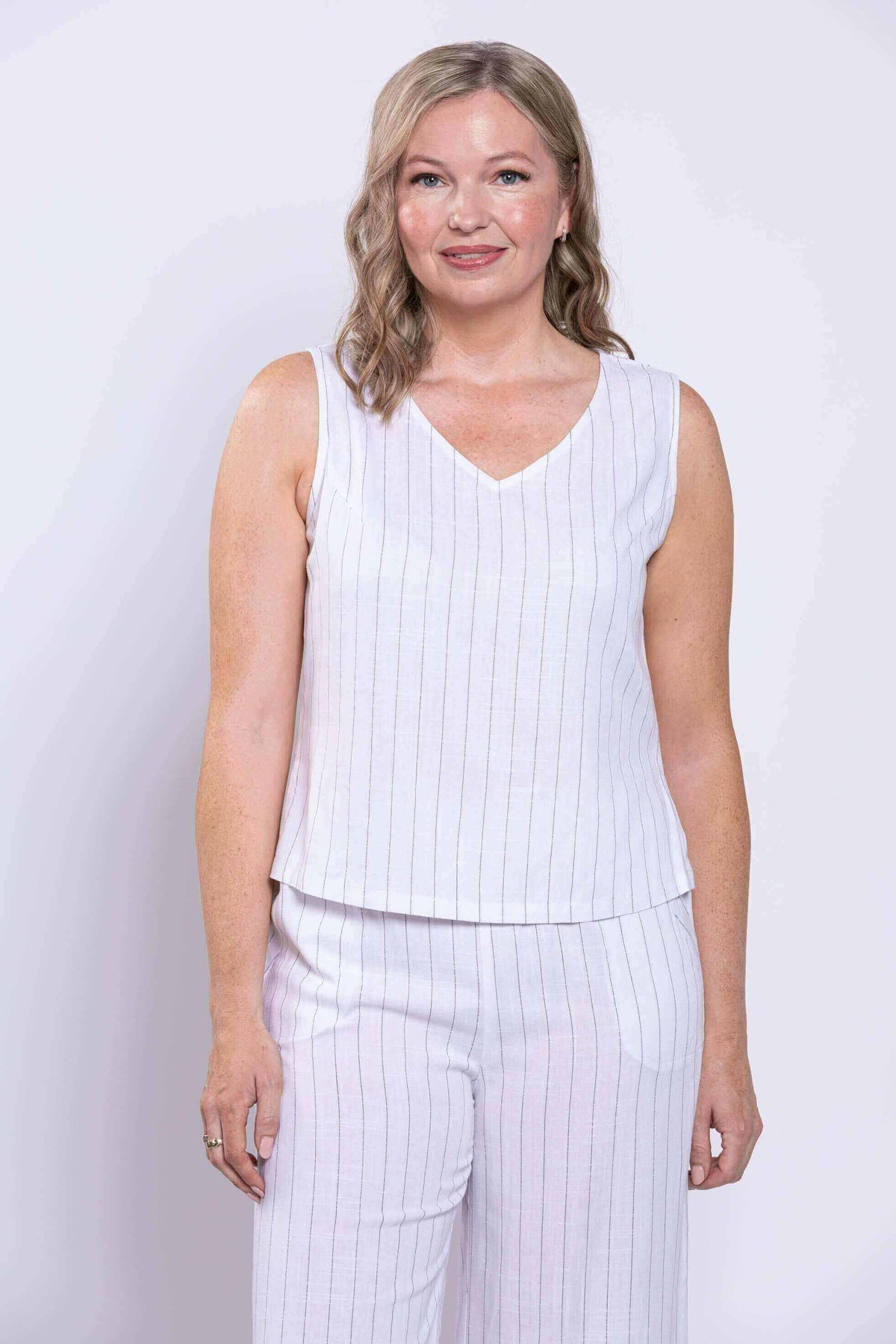 Front view cropped shot of woman in white striped sleeveless V-neck tank and matching pants