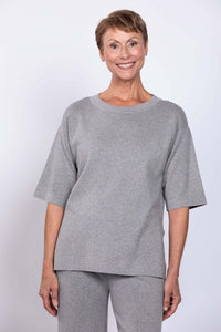 Front view of a woman wearing a light grey short-sleeve crew neck sweater with matching pants
