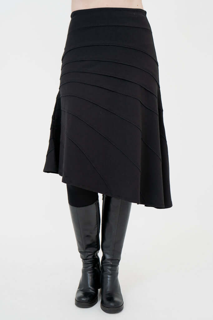 Front view of black Beverly skirt with asymmetrical seam details and knee-high boots