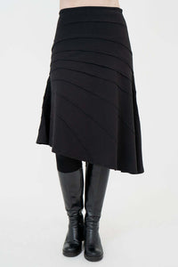 Front view of black Beverly skirt with asymmetrical seam details and knee-high boots