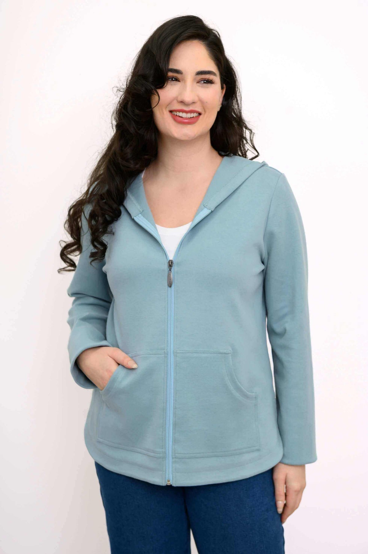 Front view of woman wearing light blue zip-up hoodie jacket with hands in pockets