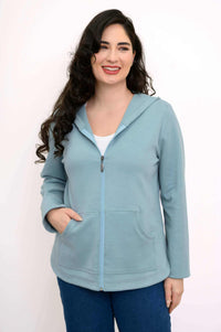 Front view of woman wearing light blue zip-up hoodie jacket with hands in pockets