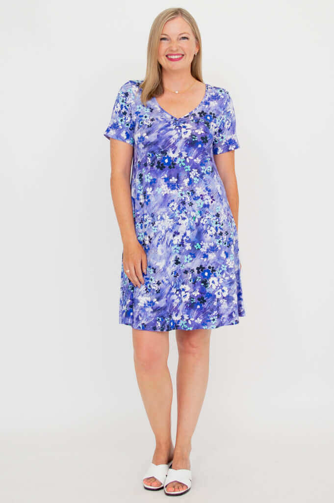 Front view of woman wearing a violet floral ruched V-neck dress