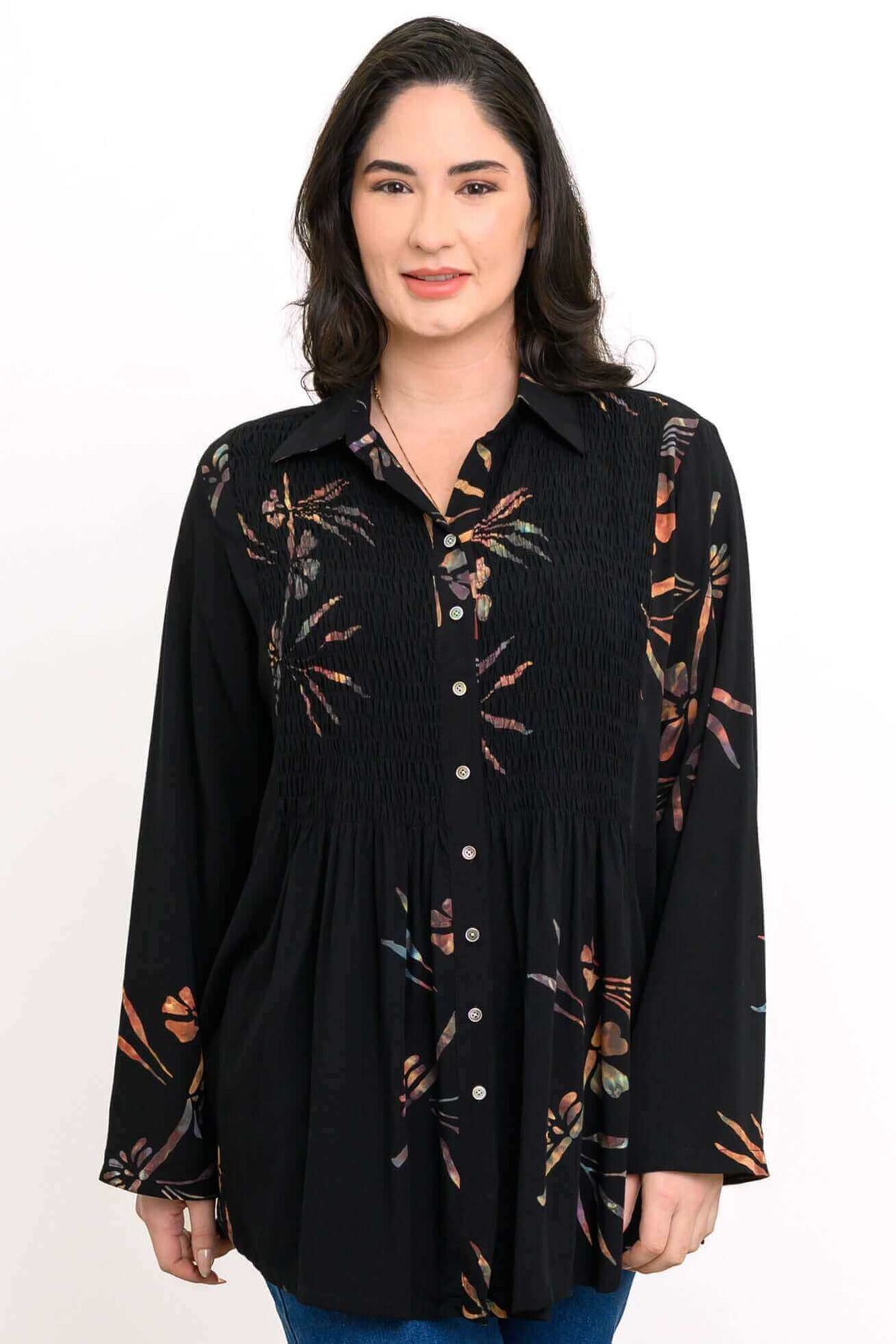 Front view of woman wearing a black long sleeve floral smocked tunic shirt