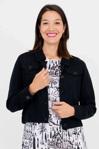 Front view of a woman wearing a black cropped jacket over a white patterned dress