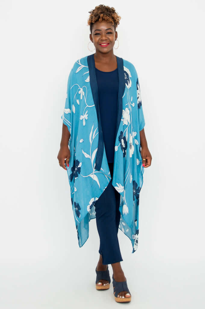Front view of a woman wearing a blue floral Darcy Kimono Wrap over navy pants and a top