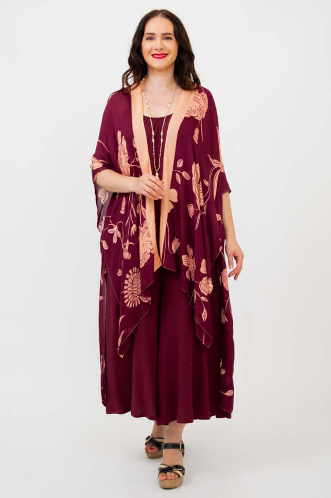 Front view of woman wearing a burgundy floral kimono wrap with peach trim