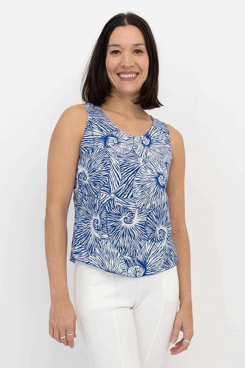 Front view of woman wearing blue swirl print sleeveless Dee Tank top with white pants